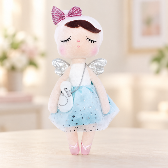 Angel plush doll with a blue star skirt, swan purse and pink bow on a pale tabletop