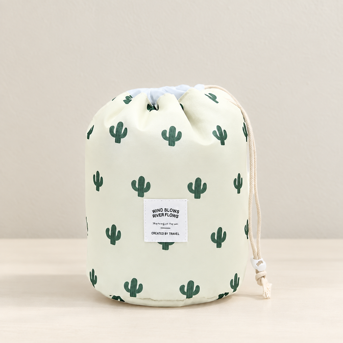 Pale cream drawstring cosmetic pouch with green cactus print on an ivory surface.