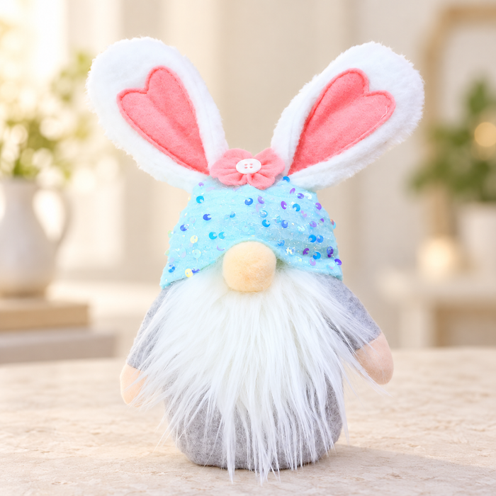 Blue sequinned bunny gnome with pink flower and white beard on a pale stone tabletop