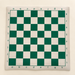 Green and cream chess mat on an ivory surface