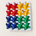 Sixteen coloured aeroplane game pieces in a white tray