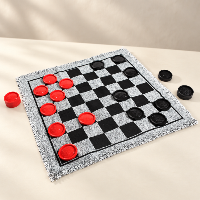 Checkers mat with red and black counters on an ivory table