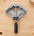 Grey corner clamp with a black handle on a clean wooden workbench.