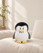 Sad-face penguin plush toy on an ivory linen chair.
