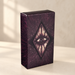 Dark plum tarot deck box with an eye and radiating diamond illustration.
