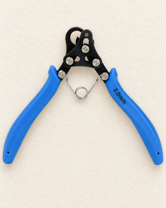 Blue 3.0mm wire coiling pliers with a black head and metal return spring on an ivory work mat.