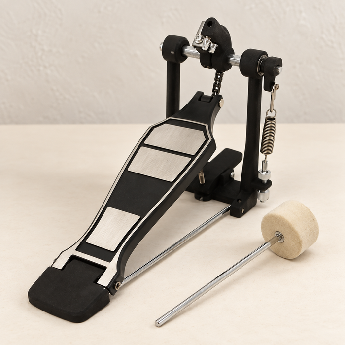 Black and silver bass drum pedal with a felt beater on an ivory tabletop