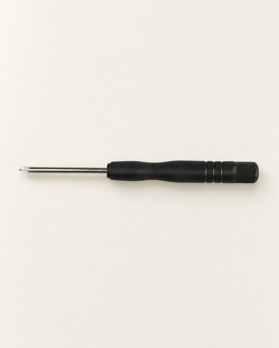 Single mini Phillips screwdriver with a black handle on an ivory work surface.