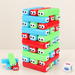 Colourful stacking block tower with cartoon eyes, loose blocks and a die on an ivory table.