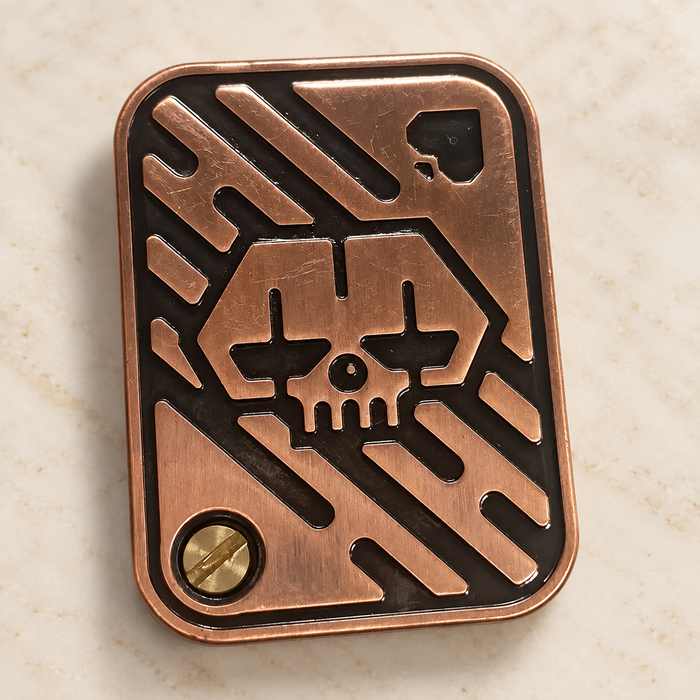 Bronze metal rectangular object with skull relief on an ivory surface