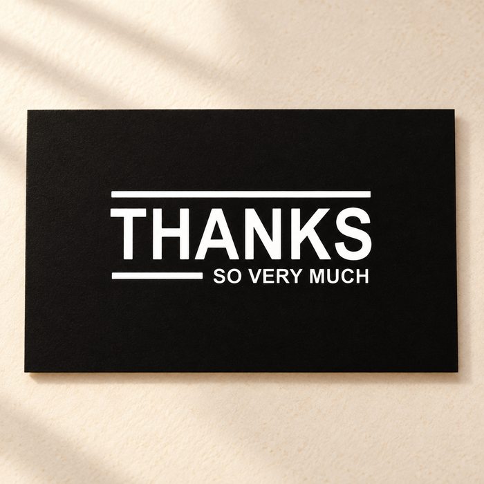 Black thank you card with white lettering on ivory tabletop