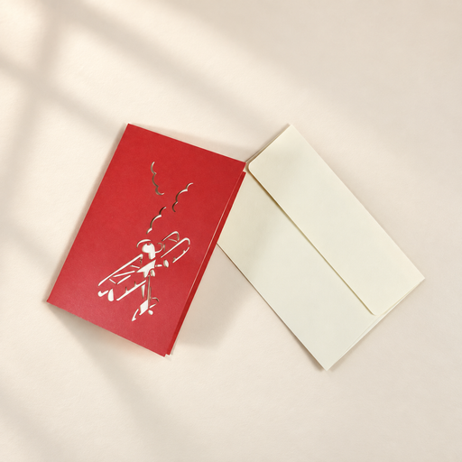 Closed red airplane greeting card beside a cream envelope