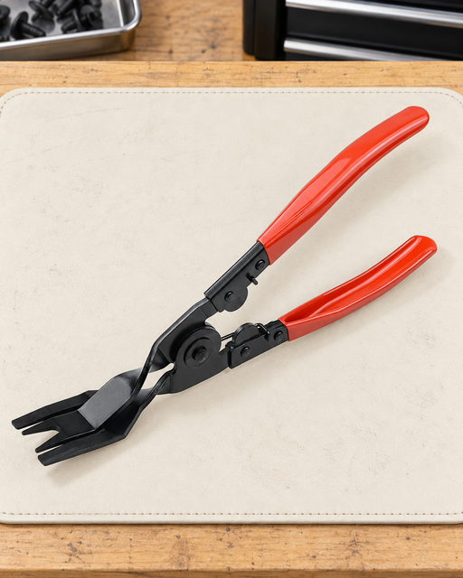 Single black trim clip removal pliers with red grips on an ivory work mat.