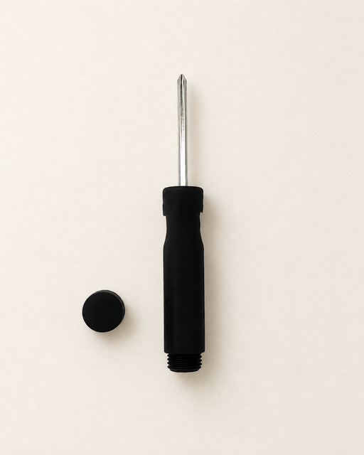 Black screwdriver-shaped storage object with its round cap beside it on an ivory surface.