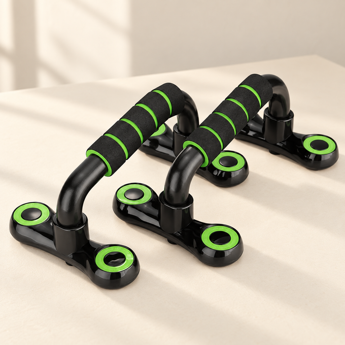 Pair of black and green push-up bars on an ivory surface.