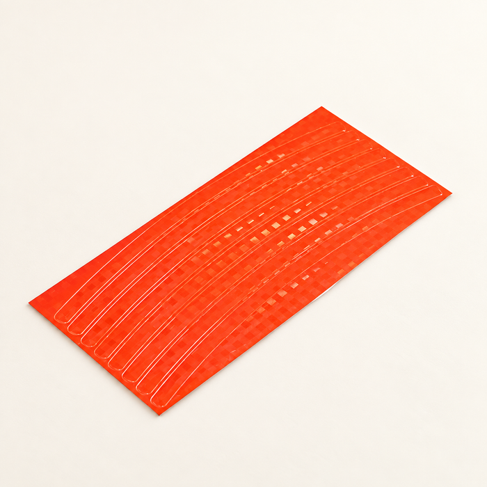 Orange curved bicycle rim reflective sticker strips on ivory surface