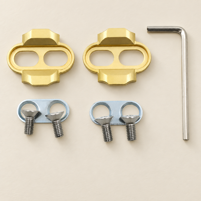 Gold bicycle pedal cleats with silver washers screws and hex key