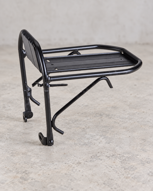 Black front bicycle rack standing on a light concrete workshop floor.