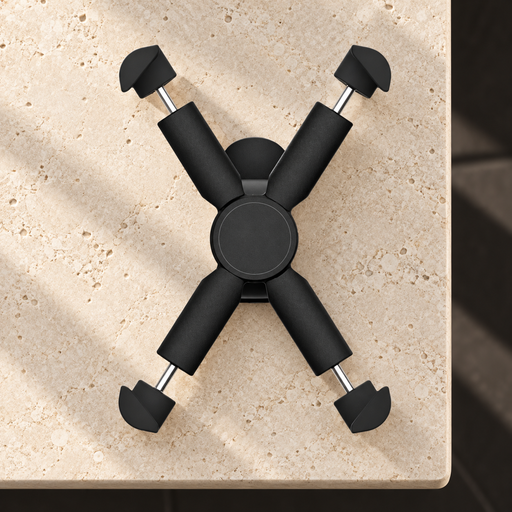 Black four-arm phone holder resting on an ivory stone console.