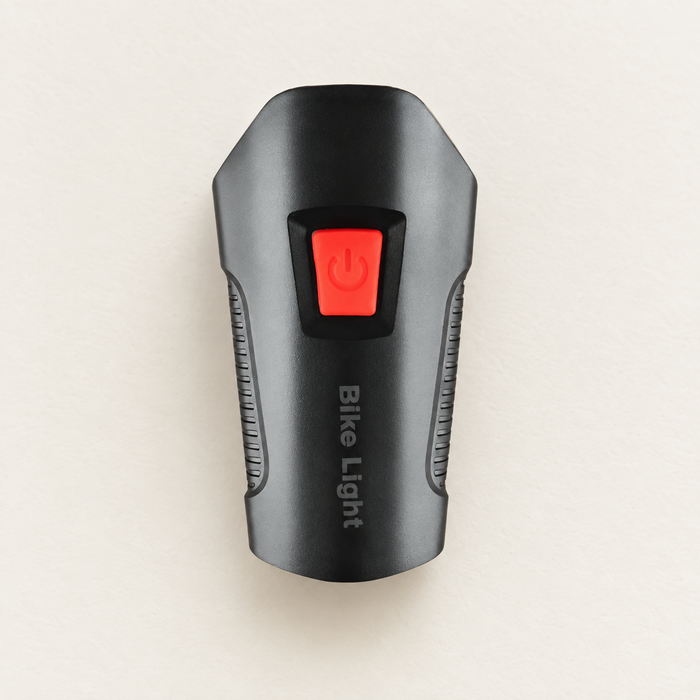 Black bicycle light with red power button on ivory surface