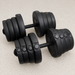 Pair of black adjustable dumbbells on a light gym floor