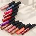 Twelve colourful matte lip cream tubes with black caps on an ivory surface.