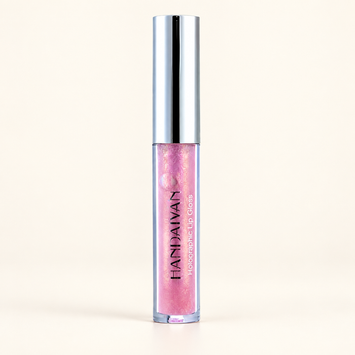 Pink iridescent lip gloss in a clear tube with a silver cap on an ivory surface.