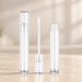Transparent empty cosmetic tubes and white applicator on ivory vanity.