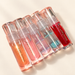 Five coloured lip gloss bottles on ivory surface