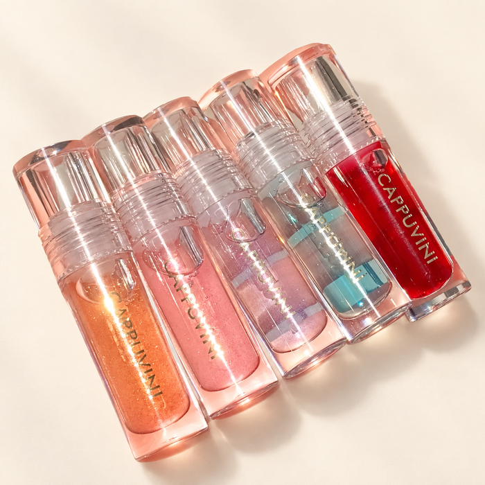 Five coloured lip gloss bottles on ivory surface