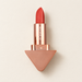 Red lipstick with rose-gold triangular base on ivory surface