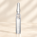 Clear lip oil tube with a silver cap on an ivory surface