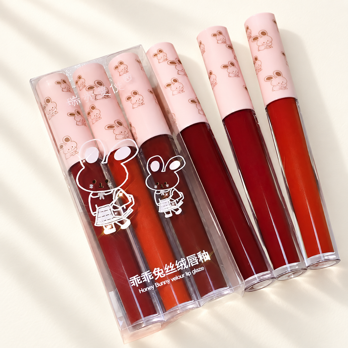 Pink bunny-print lip gloss tubes with transparent packaging on ivory