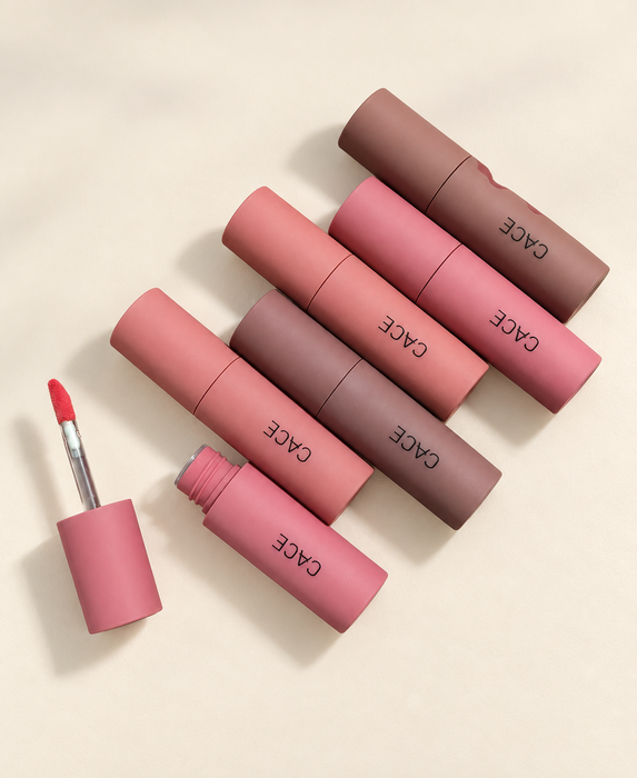 Six CACE cosmetic tubes with one open applicator on ivory surface.