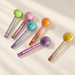 Six colourful round-headed cosmetic tubes on ivory surface.