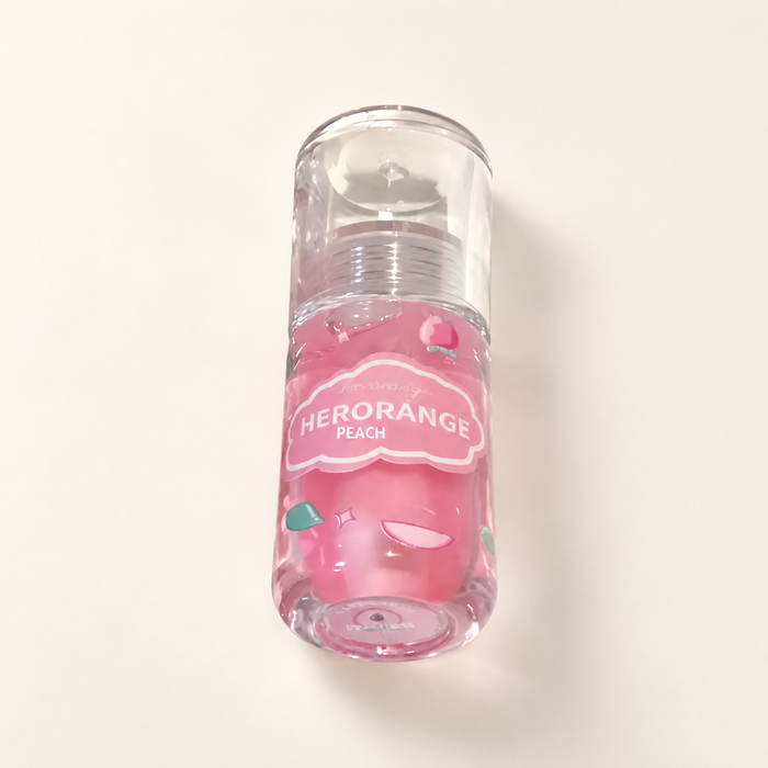 Pink peach lip gloss bottle with clear cap on ivory