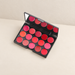 Open black lip makeup palette with fifteen shades on an ivory surface