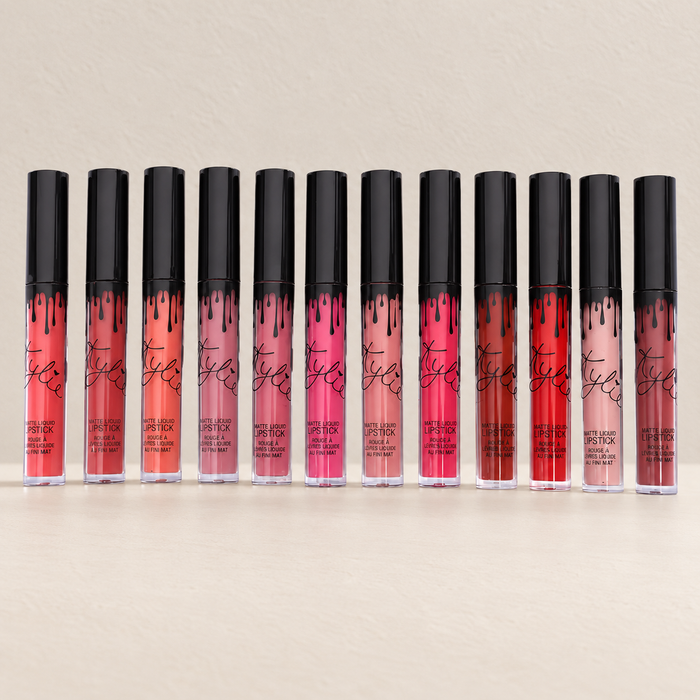 Twelve lip colour tubes with black caps arranged on an ivory surface