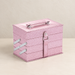 Closed pink glitter makeup case with silver fittings on an ivory table