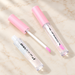 Clear lip gloss tubes with pink caps and white applicator.