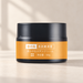 Black cream jar with a gold-orange label on an ivory vanity.