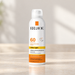 White cosmetic spray bottle with orange and yellow label.