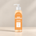 Peach lotion bottle with white pump and orange label on ivory