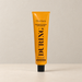 Orange OceAura tube with black cap on an ivory surface