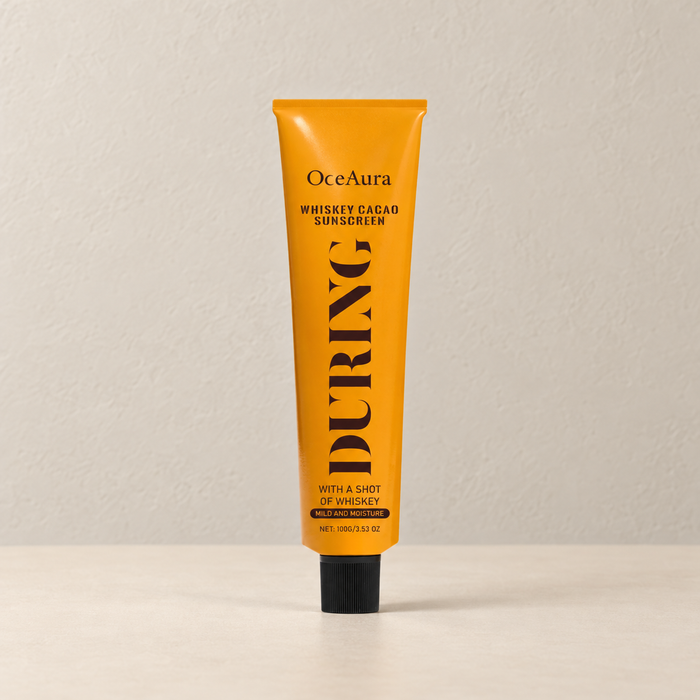Orange OceAura tube with black cap on an ivory surface