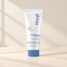 White sunscreen tube with blue lettering and cap on an ivory surface.