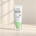 White tube with a green pump inside a clear cap on an ivory surface.