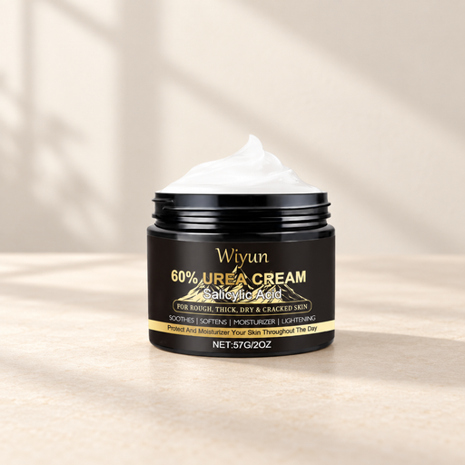 Open black cream jar with gold lettering on an ivory surface.