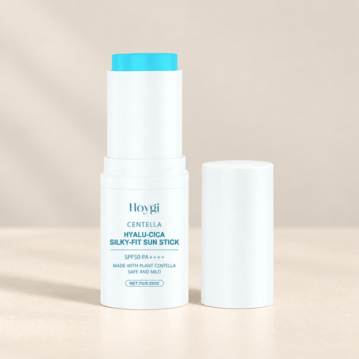 White sunscreen stick with a cyan tip beside its tall white cap on an ivory surface.