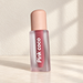 Frosted Pink coco lip lacquer bottle with peach cap on ivory vanity